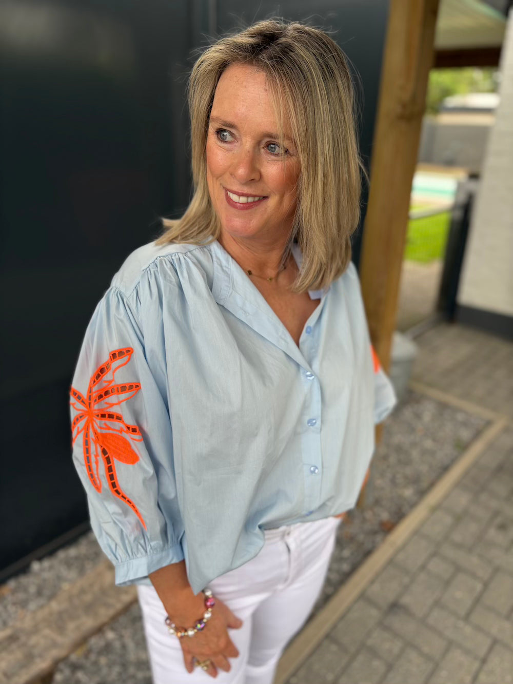 Wijde blouse lichtblauw met neon bloem op de mouw
